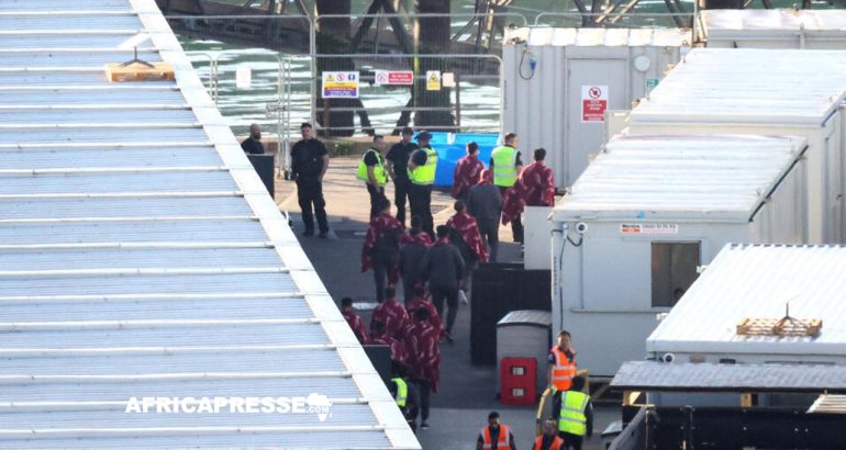 Des migrants sont escortés par des officiers des forces frontalières britanniques