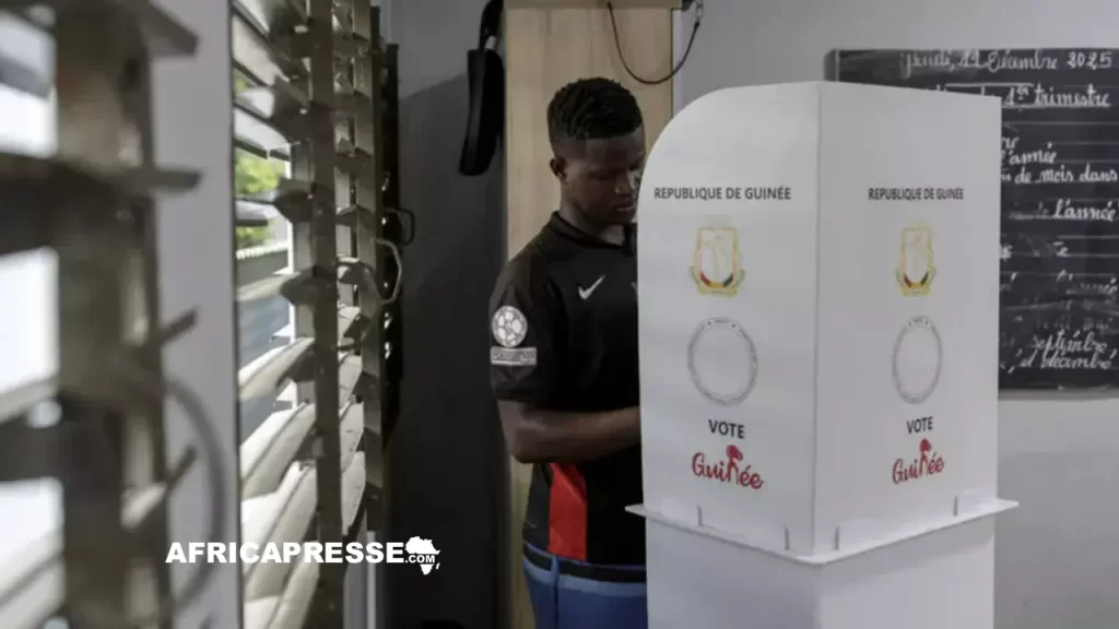 Un électeur avec son bulletin dans l'isoloir d'un bureau de vote à Conakry